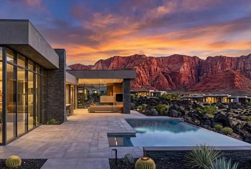 Modern luxury home with a pool, red-rock backdrop and colorful sunset